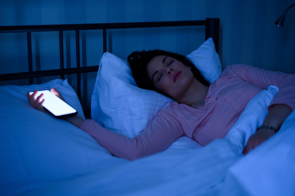 woman sleeping while holding still active smartphone