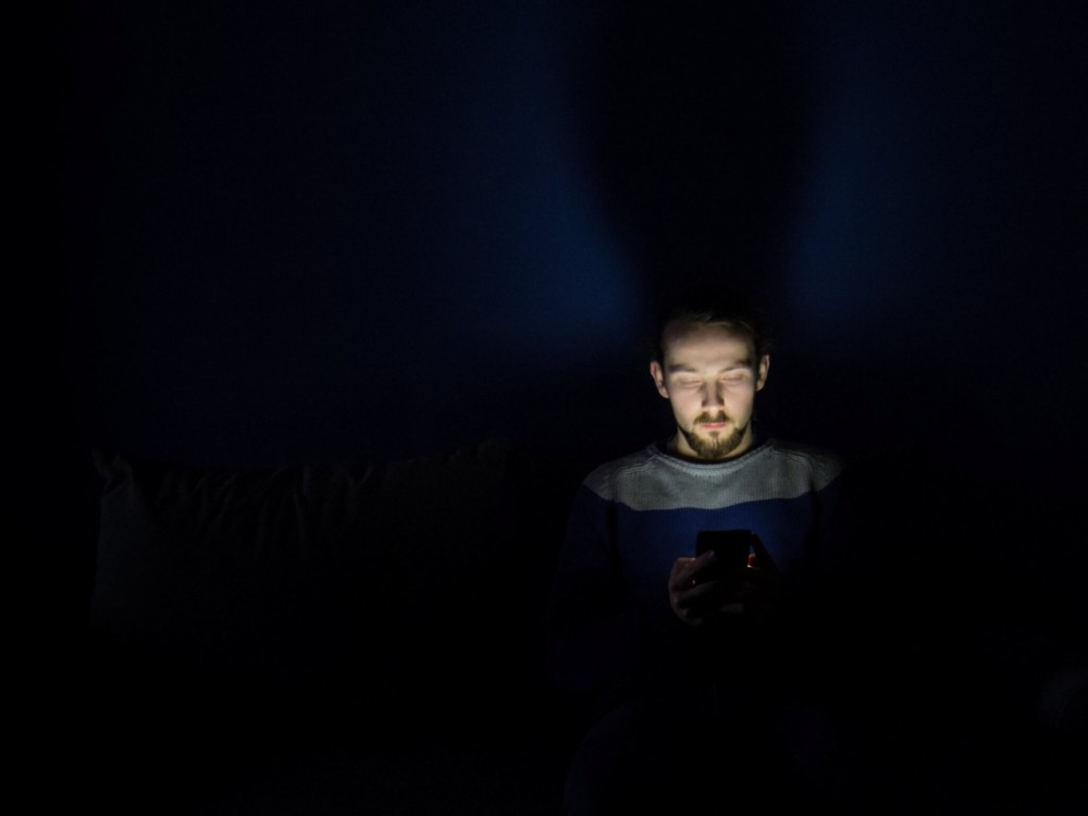 Man looking at smartphone in bed at night